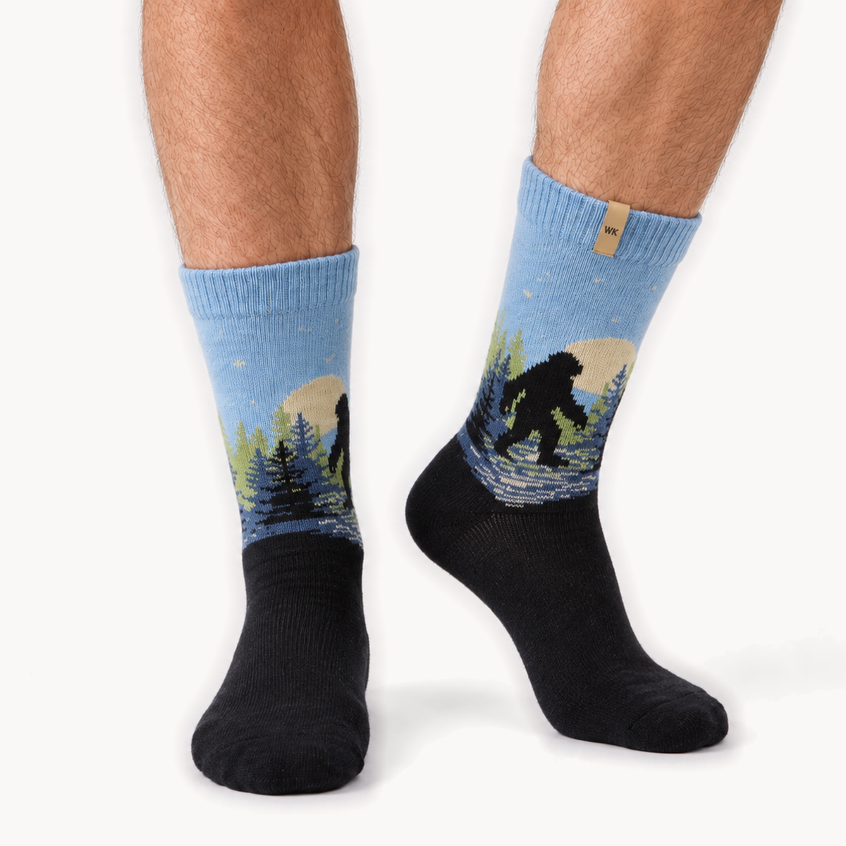 Sasquatch Trail merino wool crew socks for men, a sasquatch crossing a moonlit ridge, sky blue fading into a black foot